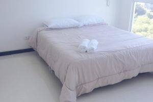 Una cama blanca con dos toallas encima. en Pozos colorado Bello horizonte - Apartamento 70 mt2, en Santa Marta