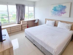 ein Schlafzimmer mit einem großen weißen Bett und einem Fenster in der Unterkunft Des Res Hotel and Residence in Bangna