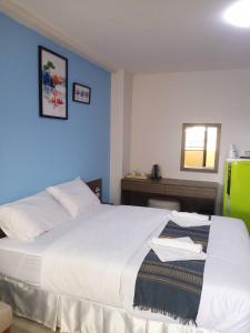 a bedroom with a large white bed with a blue wall at โสดาอพาร์ทเม้นท์​ in Ban Lam Phak Kut