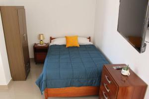 a bedroom with a bed with a blue comforter and yellow pillow at Departamento en Chimbote con cochera in Chimbote