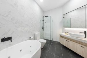 a bathroom with a tub and a toilet and a sink at Meriton Suites Bondi Junction in Sydney