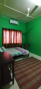 a green bedroom with a bed and a ceiling fan at Baiti Homestay in Gambang