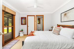a bedroom with a white bed and a sliding glass door at Cedar House in Kangaroo Valley