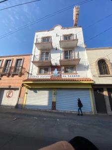 um homem a andar numa rua em frente a um edifício em Hotel Zaragoza em San Juan de los Lagos