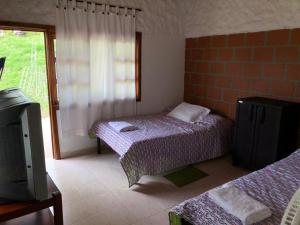 a bedroom with two beds and a tv and a window at Finca Hotel Andaquies in Armenia