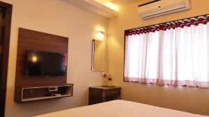um quarto com uma cama, uma televisão e uma janela em Hotel Rhythm Grand Suite em Tiruchchirappalli