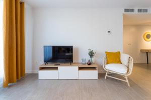 uma sala de estar com uma televisão e uma cadeira em Dunabeach em Torrox Costa