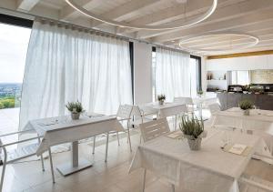 una sala da pranzo con tavoli bianchi e sedie bianche di Progress Country & Wine House ad Asolo