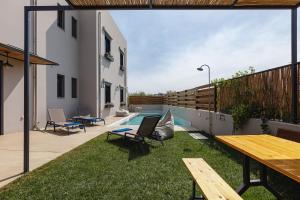a backyard with a table and chairs and a pool at Iron Villas - Nefeli & Oniros in Pangalochori