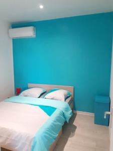 a bedroom with a blue wall and a bed at Maison charmante à Morne-à-l'Eau avec jardin clôturé in Morne-à-lʼEau