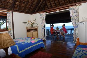 two women sitting at a table in a room with a balcony at Pension de famille HITI MOANA VILLA in Papara