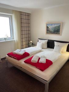 a large bed with two red pillows on it at W5 Haus Ganghofer in Leutasch