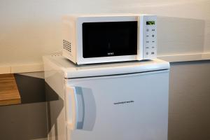 Un four micro-ondes est installé au-dessus d'un réfrigérateur. dans l'établissement Forenom Aparthotel Kemi, à Kemi
