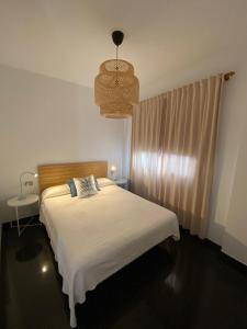 1 dormitorio con cama blanca y lámpara de araña en Los Zifios en La Restinga