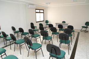an empty room with green chairs and a table at Big Executive Hotel in Araguari +39 photos