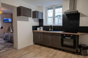 a kitchen with a sink and a stove top oven at NG SuiteHome - Lanester Lorient - Balnéo - Netflix - Wifi in Lanester