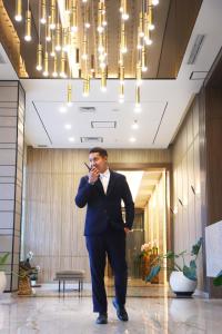 a man in a suit talking on a cell phone at StayG Eastern Green by GranDhika - Bekasi in Padurenan