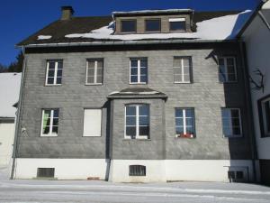 溫特貝格的住宿－Jagdschloss Siedlinghausen，一座大灰色房子,屋顶上积雪