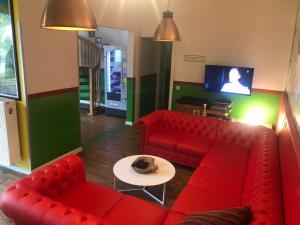 ein Wohnzimmer mit einem roten Sofa und einem Tisch in der Unterkunft Backpackers Düsseldorf - SELF CHECK-IN in Düsseldorf