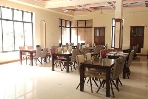 a dining room with tables and chairs and large windows at The Byke Brightland Adventure Park & Resort in Mumbai