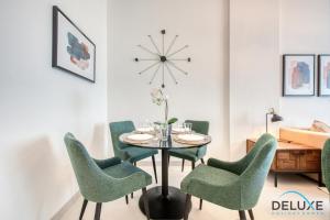uma sala de jantar com cadeiras verdes, uma mesa e um relógio em Welcoming 1BR at Prime Views Meydan by Deluxe Holiday Homes em Dubai