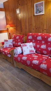 un sofá rojo con almohadas rojas y blancas en una habitación en Front de Neige Isola 2000, en Isola 2000