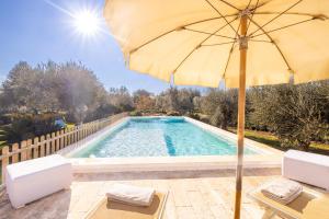 una piscina con ombrellone e due sedie e un tavolo di Villa Acqua Azzurra a Ceglie Messapica
