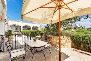 a patio with a table and chairs and an umbrella at Tenuta Mosè Charming House&Relais Gallipoli in Gallipoli