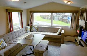 a living room with a couch and a table at Plot 188D Lakeside Cabin, Wyldecrest, Millom in Millom