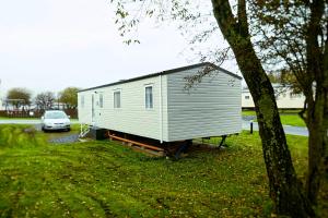 a tiny house parked next to a car at Plot 188D Lakeside Cabin, Wyldecrest, Millom in Millom