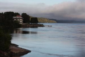 une grande étendue d'eau avec un bâtiment sur le rivage dans l'établissement Motel Panoramique, à Saguenay
