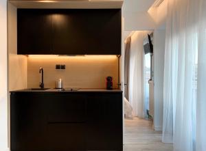 a kitchen with black cabinets and a sink at ICON Urban Living in Thessaloniki +37 photos