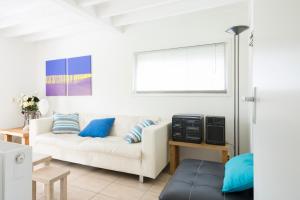een woonkamer met een witte bank en blauwe kussens bij Kustverhuur, Park Schoneveld, Zeester 27 in Breskens