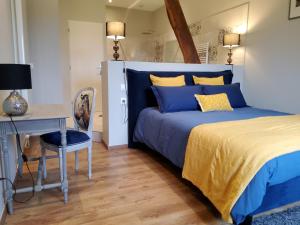 a bedroom with a blue bed and a desk and a chair at Les Tilleuls de Marie in Saint-Edmond +31 photos