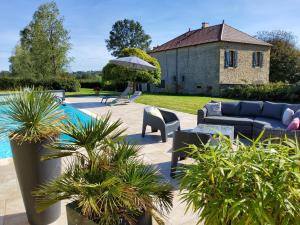 a patio with a couch and chairs next to a pool at Les Tilleuls de Marie in Saint-Edmond