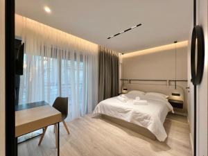 a bedroom with a white bed and a desk and a window at ICON Urban Living in Thessaloniki