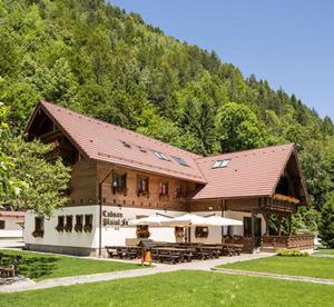 a building with tables and umbrellas in front of a mountain at Panoramic Residence in Zărneşti