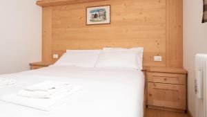 a bedroom with a white bed with a wooden wall at Italianway - Adda 10 in Valdidentro