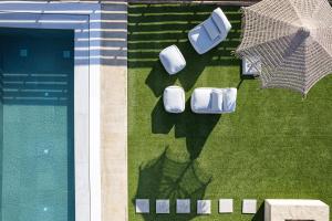 Sísion的住宿－Carob Villas, an Eco-Friendly Hideaway，享有带两把椅子和一把遮阳伞的游泳池的上方景色。