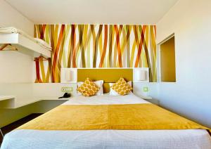 ein Schlafzimmer mit einem großen Bett und einer farbenfrohen Wand in der Unterkunft Hotel 3K Faro Aeroporto in Faro