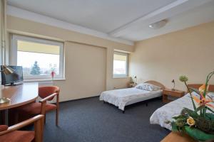 a hotel room with two beds and a desk at Hostel Relaks in Olsztyn