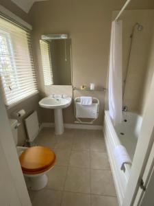 a bathroom with a sink and a toilet and a tub at Guyers House Hotel and Restaurant in Corsham