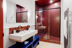 La salle de bains est pourvue d'un lavabo et d'une douche avec du carrelage rouge. dans l'établissement Edgar Suites Auteuil - Le Marois, à Paris