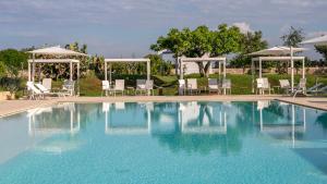 a large swimming pool with chairs and umbrellas at Masseria Mongiò dell'Elefante in Otranto