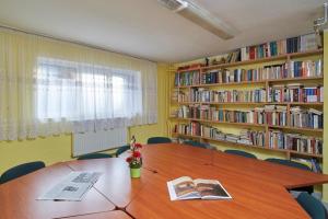 ein Zimmer mit einem Tisch und Bücherregalen mit Büchern in der Unterkunft Szkolne Schronisko Mlodziezowe w Olsztynie in Olsztyn