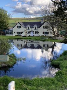 ein Haus mit einem Teich davor in der Unterkunft Llwyn Onn Guest House, North Wales in Pentrefoelas