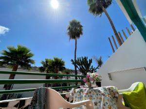 a table and chairs on a balcony with palm trees at Leticia del Mar Adults Only in Puerto Rico de Gran Canaria