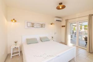 1 dormitorio con cama blanca y balcón en Villa Carolina, en Izola