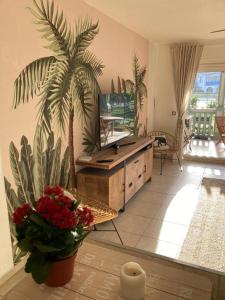 a living room with a tv and a palm tree at Sea Front Apartment Orient Bay in Orient Bay French St Martin