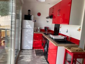 a kitchen with red cabinets and a white refrigerator at B&B Macchia Verdata avec piscine in Monacia-dʼAullène